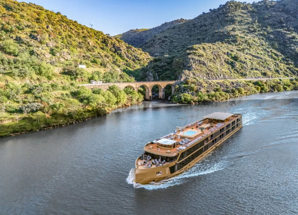 AmaSintra river cruise ship sailing through the Douro Valley in Portugal past an arched bridge