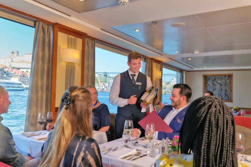 A waiter serves guests at a dining table on board an AmaWaterways ship in Porto, Portugal
