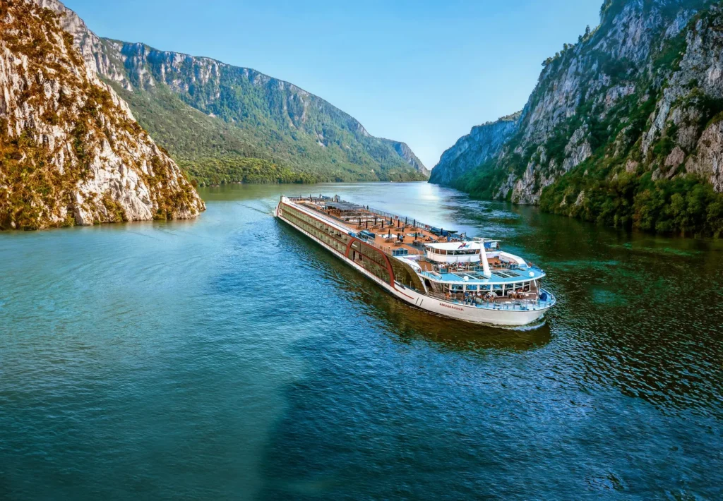 River cruise ship sailing through a gorge between steep rocky cliffs
