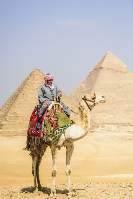 Three pyramids, monuments and burial tombs of the pharaohs Khufu, Khafre, and Menkaure, a tourist guide riding a camel